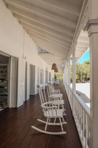 a row of rocking chairs sitting on a porch at Hotel Agua Azul Beach Resort in Baru