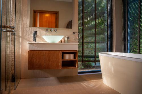 a bathroom with a sink and a tub and a mirror at BangTao Anchan 豪华两卧 私人泳池 现代度假巴厘风 in Layan Beach