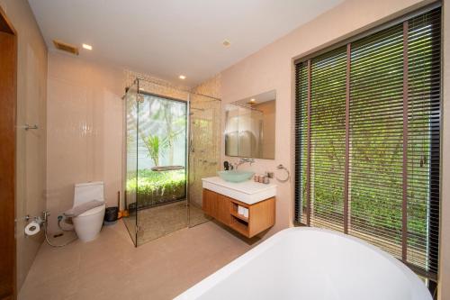 a bathroom with a tub and a sink and a toilet at BangTao Anchan 豪华两卧 私人泳池 现代度假巴厘风 in Layan Beach