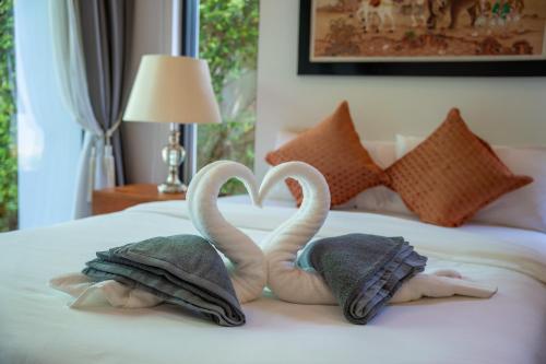 two towel swans making a heart on a bed at BangTao Anchan 豪华两卧 私人泳池 现代度假巴厘风 in Layan Beach