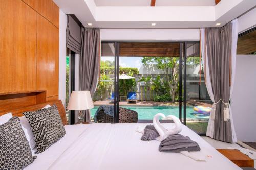 a bedroom with a bed and a swimming pool at BangTao Anchan 豪华两卧 私人泳池 现代度假巴厘风 in Layan Beach