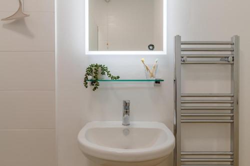 a white bathroom with a sink and a mirror at 1 Seabirds House in St Ives
