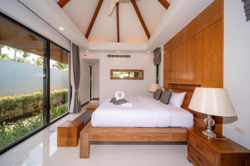 a bedroom with a bed and a large window at BangTao Anchan 豪华两卧 私人泳池 现代度假巴厘风 in Layan Beach