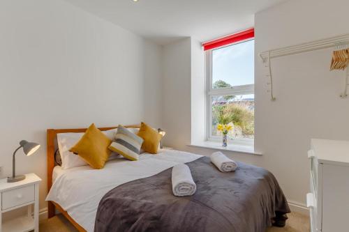 a bedroom with a bed with yellow pillows and a window at 1 Seabirds House in St Ives
