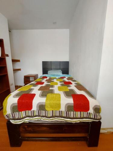 a bed with a colorful comforter in a room at Sumaq Wasi Caminos Del Inca in Lima