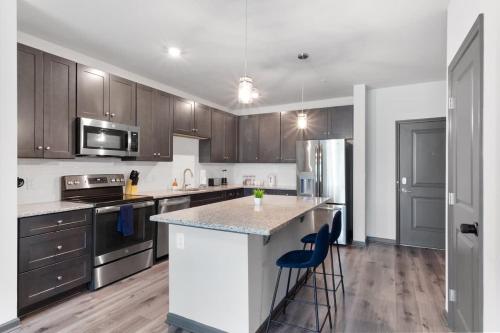 a kitchen with wooden cabinets and a kitchen island with blue bar stools at Luxe King 2 Bedroom Suite in North Raleigh in Wake Forest
