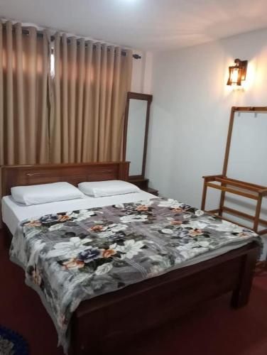 a bedroom with a bed with a floral blanket on it at Garden View's Rest in Nuwara Eliya