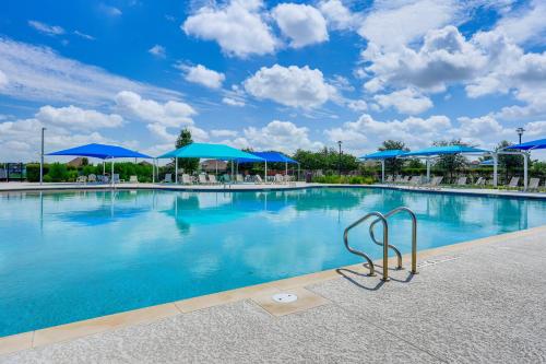 a large swimming pool with blue umbrellas and chairs at Pool Access and Private Yard Family Home in Kyle! in Kyle