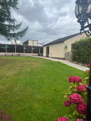 a yard with a building and pink flowers at 2 bedroom bungalow, 15 minutes to Alton Towers, dog friendly in Wetleyrocks