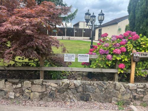 a garden with flowers and signs on a stone wall at 2 bedroom bungalow, 15 minutes to Alton Towers, dog friendly in Wetleyrocks