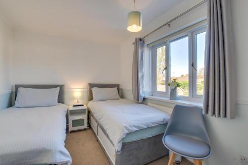 a bedroom with two beds and a chair and a window at Tegeirian in Porthcawl