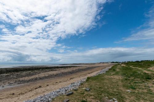 a beach with rocks and a blue sky and clouds at Tegeirian in Porthcawl