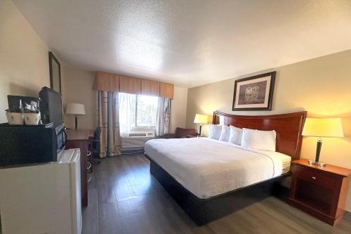 a hotel room with a bed and a television at Travelodge by Wyndham Klamath Falls in Klamath Falls