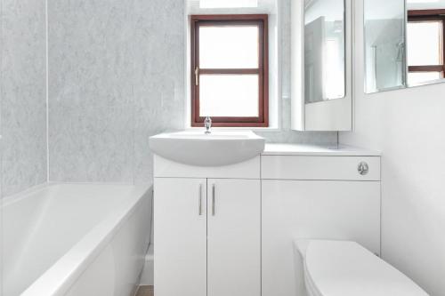a white bathroom with a sink and a mirror at Trefaes Bach in Abersoch