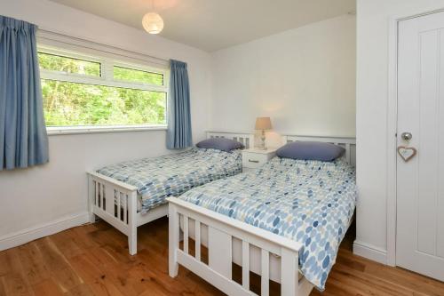 - 2 lits dans une chambre avec des rideaux bleus dans l'établissement 4 Glyn y Marian, à Llanbedrog