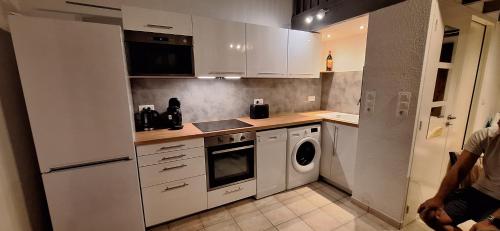 a kitchen with white cabinets and a washing machine at Mazet l'olivier 2 in Saint-Martin-de-Brômes