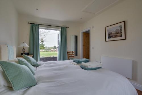 ein großes weißes Bett mit blauen Kissen in einem Schlafzimmer in der Unterkunft Pound Hill Cottage in Frittenden