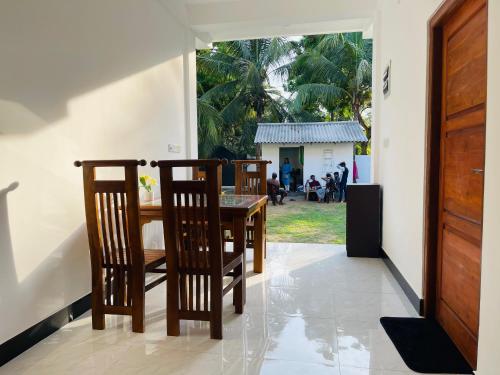 a dining room with a table and chairs and a window at Nachchi Sweet Beach Stay in Nilaveli
