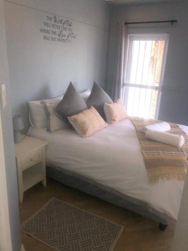 a bedroom with a bed with pillows and a window at Palmsbeach 5 in Strand