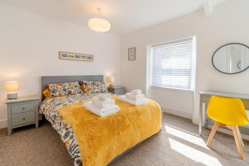 a bedroom with a bed and a yellow chair at Tideway in Tenby