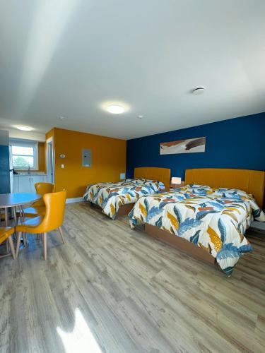 two beds in a room with a table and chairs at Fair Isle Motel in Charlottetown