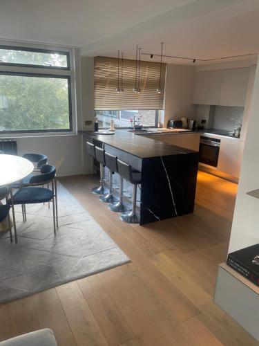a kitchen with a large black island with bar chairs at 60a Willesden Lane in London