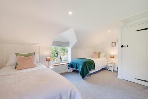 a bedroom with two beds and a window at The Cottage in Trentishoe