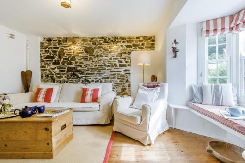 Il comprend un salon doté d'un mobilier blanc et d'un mur en briques. dans l'établissement Williams Cottage, à Bucks Mills