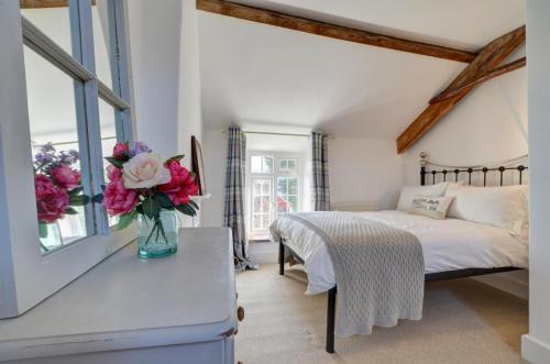une chambre avec un lit et un vase de fleurs sur une table dans l'établissement July Cottage, à West Down