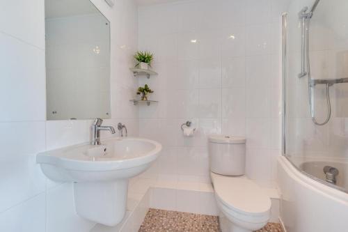 Un baño blanco con lavabo e inodoro. en Bay View, en Saundersfoot