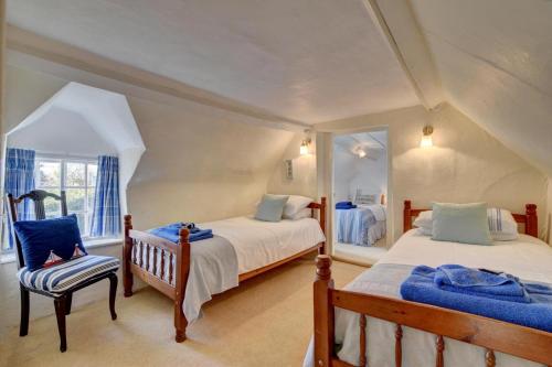 une chambre avec deux lits et une chaise dans l'établissement Monks Cottage, à Braunton