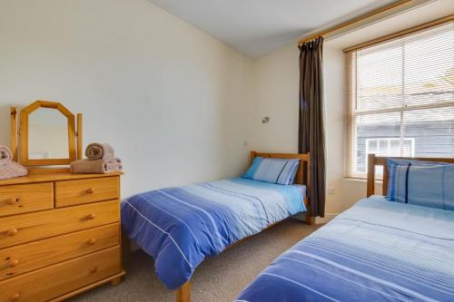 a bedroom with two beds and a dresser and a window at Carvosso in Mousehole
