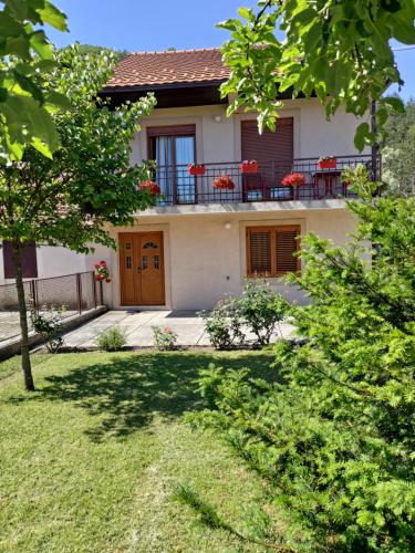 a house with a balcony with red flowers on it at Apartman Damjanovic in Cetinje