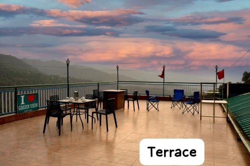 a patio with tables and chairs on a balcony at Hotel Green view with mountain view in Dharampur