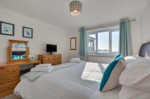 a bedroom with two beds and a dresser and a window at Duchy Lemain Garden Apts in Looe