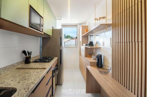 a kitchen with wooden cabinets and a counter top at Apto Charmoso com Vista para Piscina! - BIO0079 in Camaçari