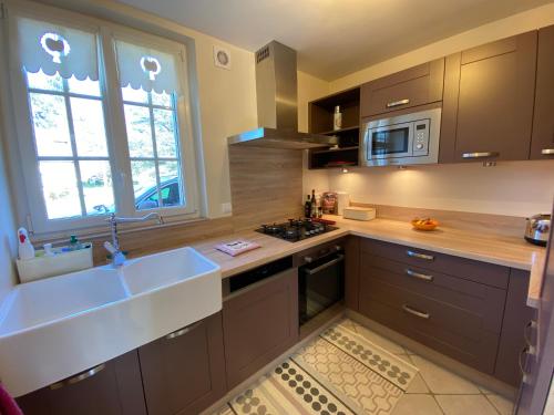 a large kitchen with a sink and a microwave at Presbytère du 19e siècle in La Chapelle-du-Bois-des-Faulx