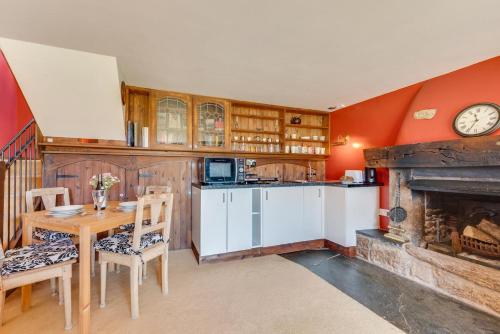 Una cocina con una mesa y un reloj en la pared. en Coombe House Retreat, en Quethiock