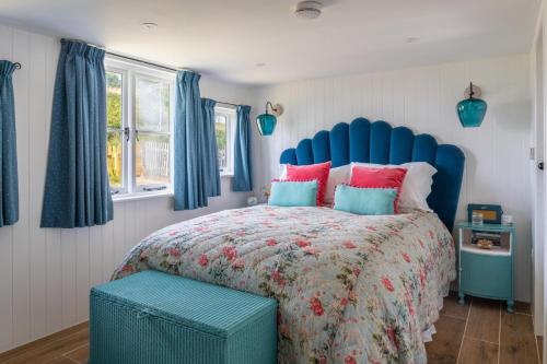 Un dormitorio con una cama grande con cabecero azul. en Bel-Nor-Cot, en Cawsand