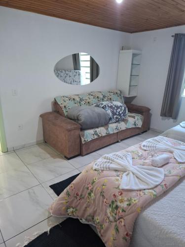a bedroom with two beds and a couch and a mirror at Casa Névoa in Canela