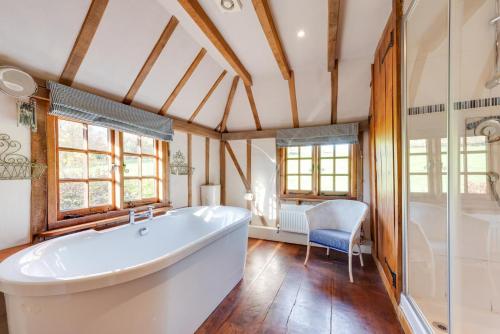 a large bathroom with a tub and a chair at Iden Green Farm Stables in Benenden
