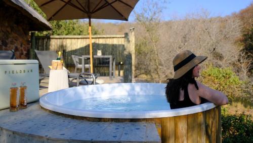a woman in a hat sitting in a hot tub at Mologa River Lodge in Rust de Winter