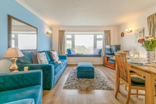 a living room with a blue couch and a table at Aurora in Looe