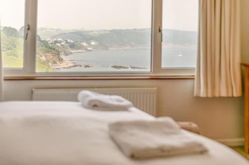a bed with two towels on it in front of a window at Aurora in Looe