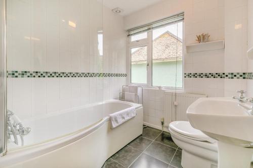 a bathroom with a tub and a toilet and a sink at Aurora in Looe