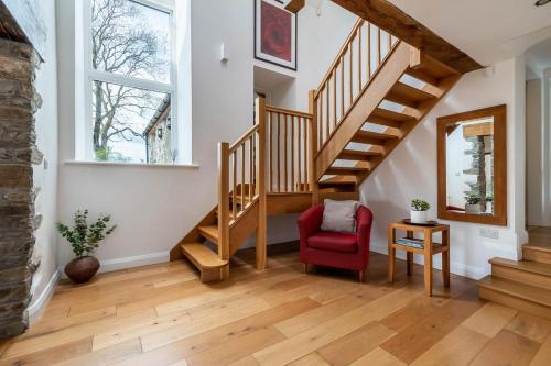 a living room with stairs and a red chair at Bryn Eithin in Derwen