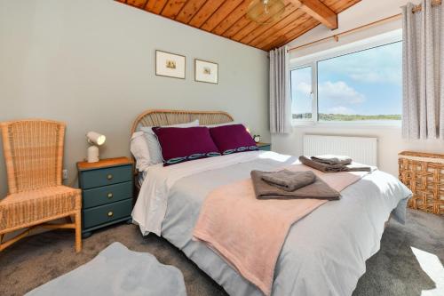 a bedroom with a bed and a chair and a window at 7 Marina Cottages in Pwllheli