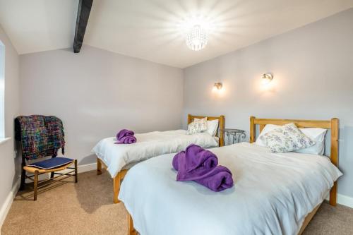 two beds in a room with purple towels on them at 2 Ivy Terrace in Bradley
