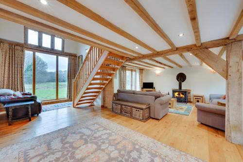 een woonkamer met een trap, een bank en een open haard bij Birdsong Barn in Westfield