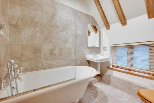 een badkamer met een bad en een wastafel bij Birdsong Barn in Westfield